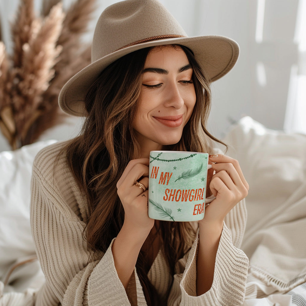 Woman wearing a beige hat and sweater, holding a mug with text, in a cozy indoor setting.